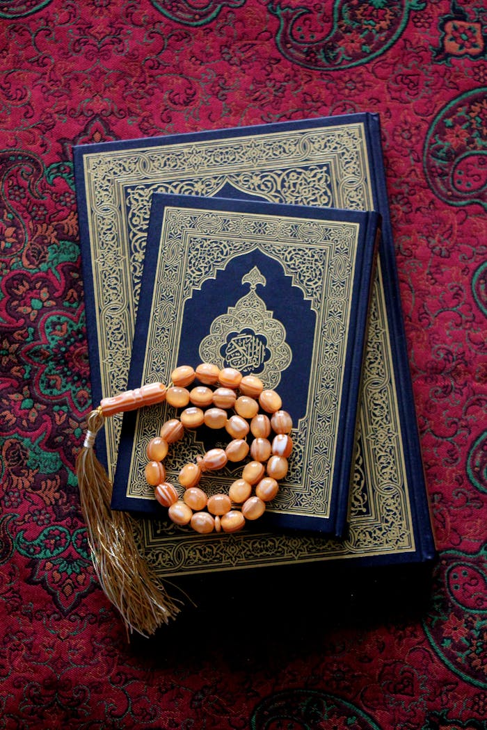 Islamic prayer beads rest on the ornate cover of the Quran.